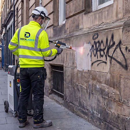 Operario realizando limpieza láser de grafiti en una fachada de piedra en Madrid